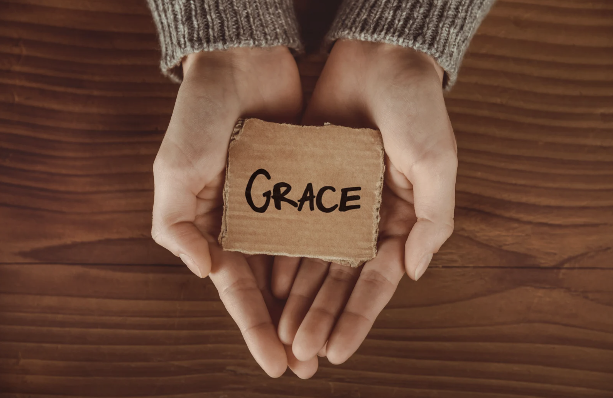 A handwritten 'Grace' cardboard placed on the hands
