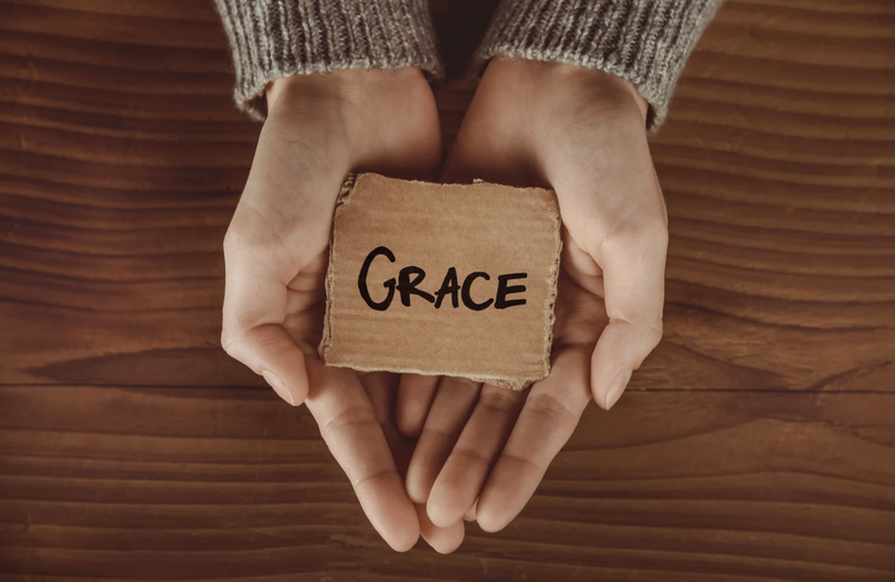 A handwritten 'Grace' cardboard placed on the hands