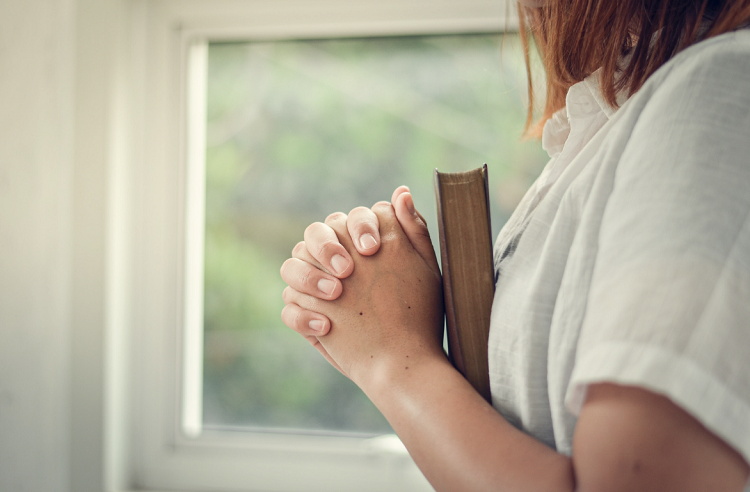 A woman prays with the Bible. 