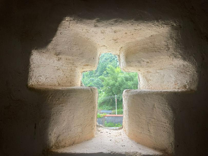 A cross-shaped cutout on a stone wall at a county church of M City