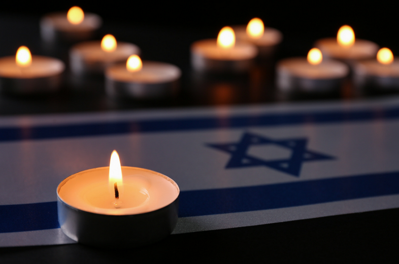 A picture of burning candles and an Israel flag on the table