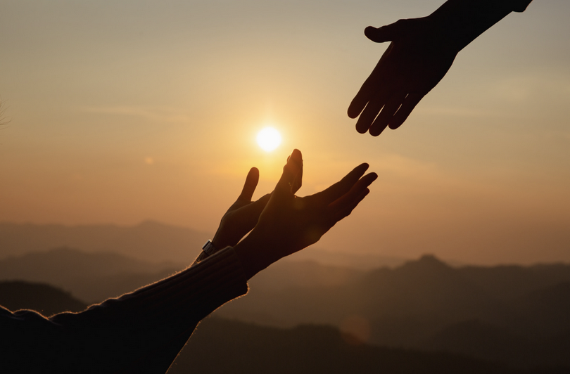 The silhouette of helping hands at sunset