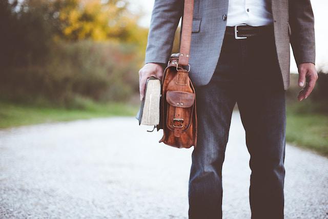 A picture of a man with a bag holding a book