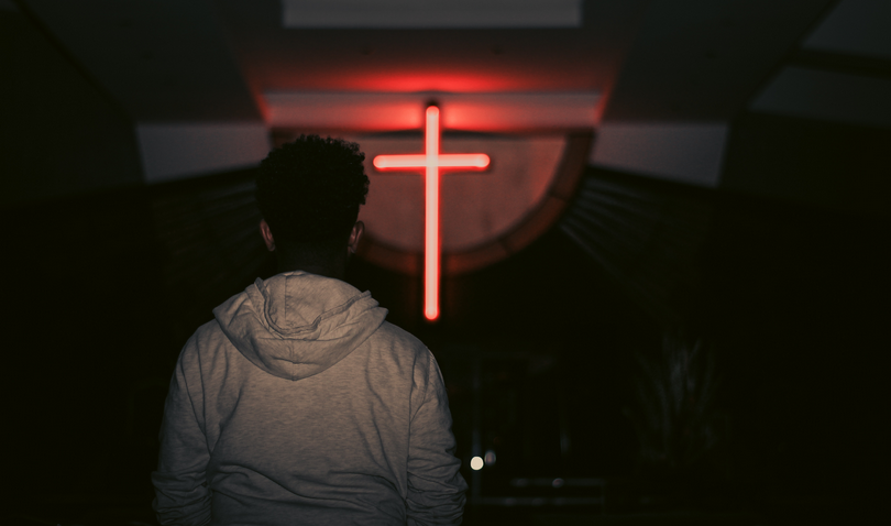 A man faces a cross at a church.