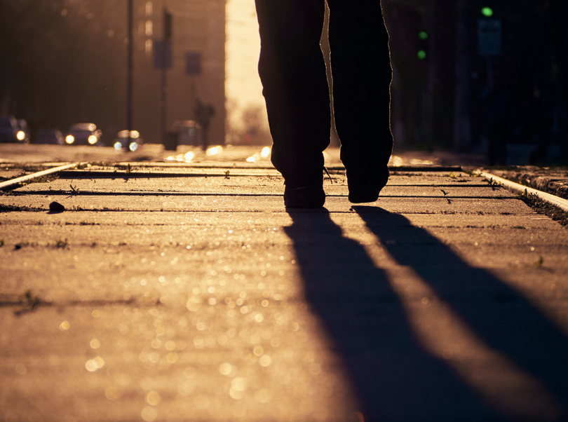 A close-up picture of a silhouette of a person walking on the street