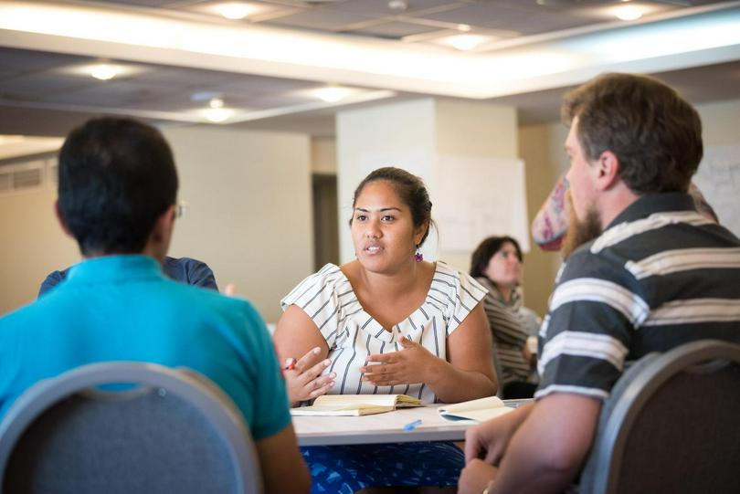 A female is discussing with other members in a meeting.