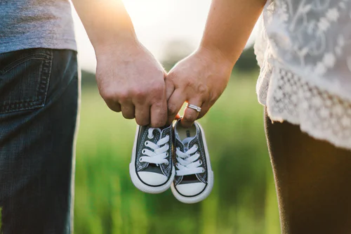 One couple hold a pair of shoes of a child.