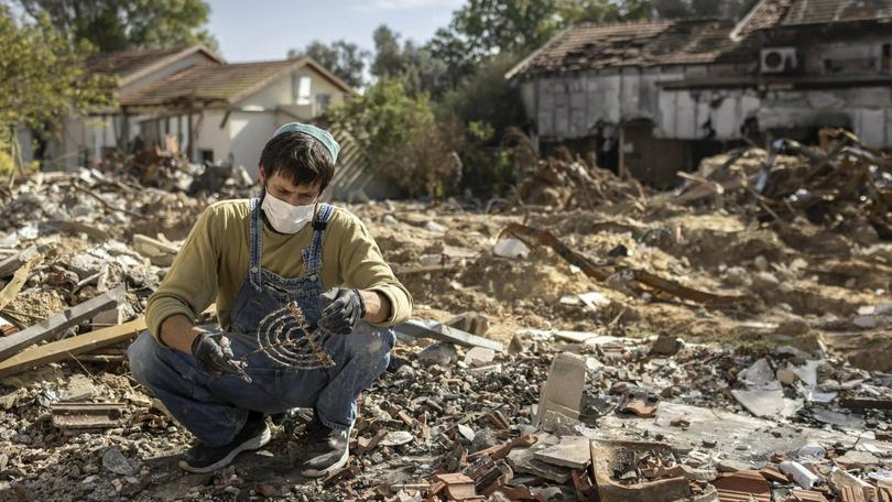 A man whose father was murdered by Hamas terrorists on Oct. 7. searched the rubble for family mementos and rescues the family menorah in Kibbutz Be’eri, Nov. 30, 2023.