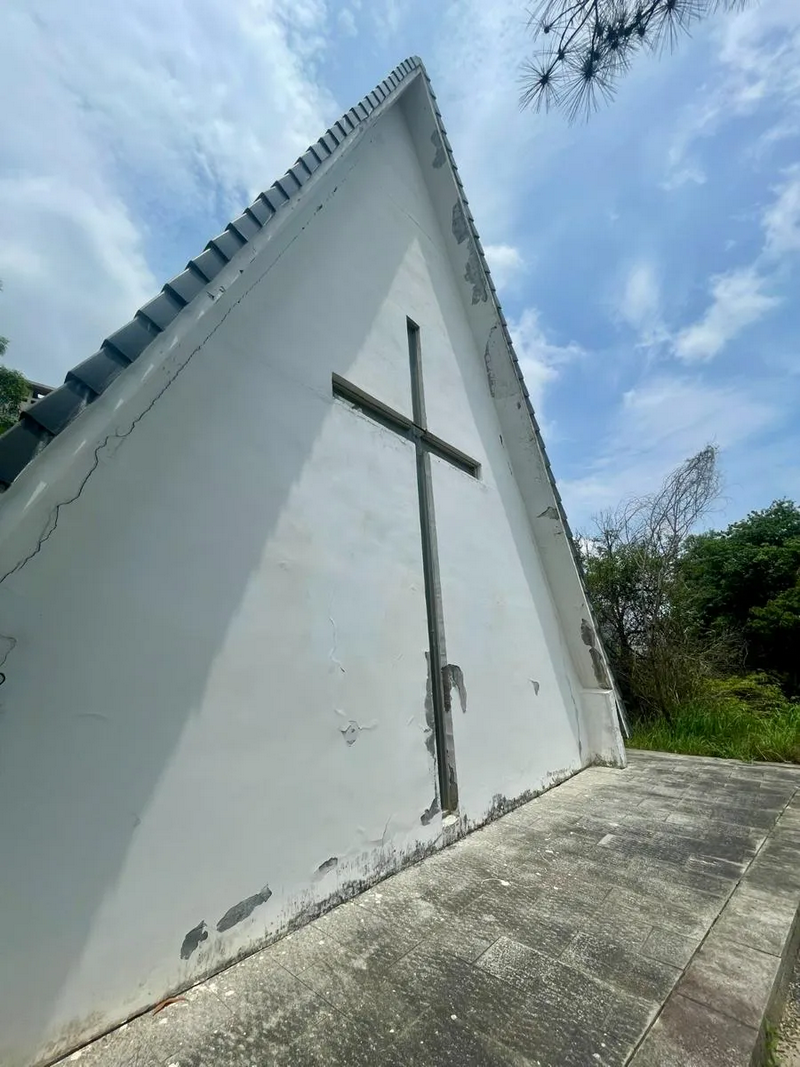 A triangular white chapel wall with a cross is seen under blue skies at Li Lang Holy Mountain Park in Shenzhen, Guangdong.