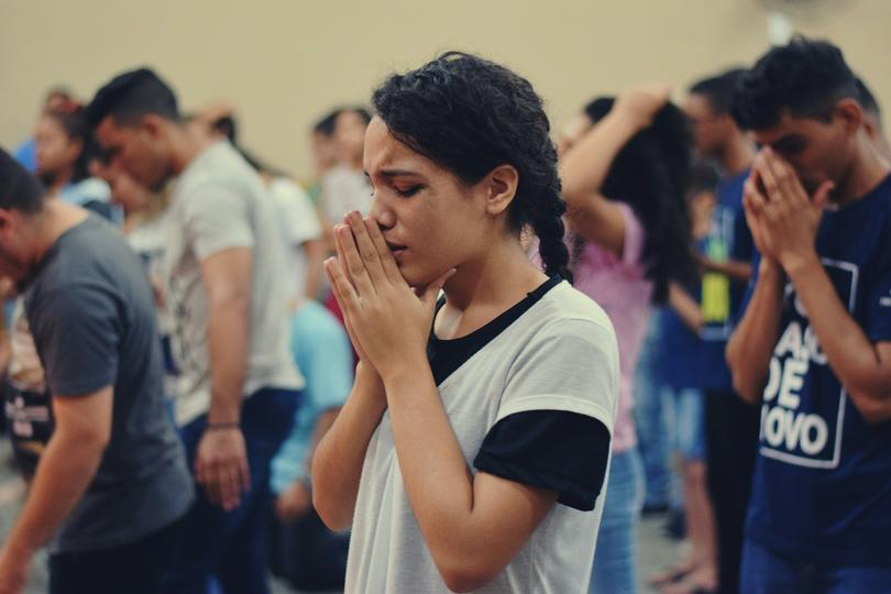 A woman prays during a worship gathering on an unknown day.