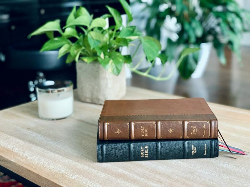 Two Bibles are placed on a desk.