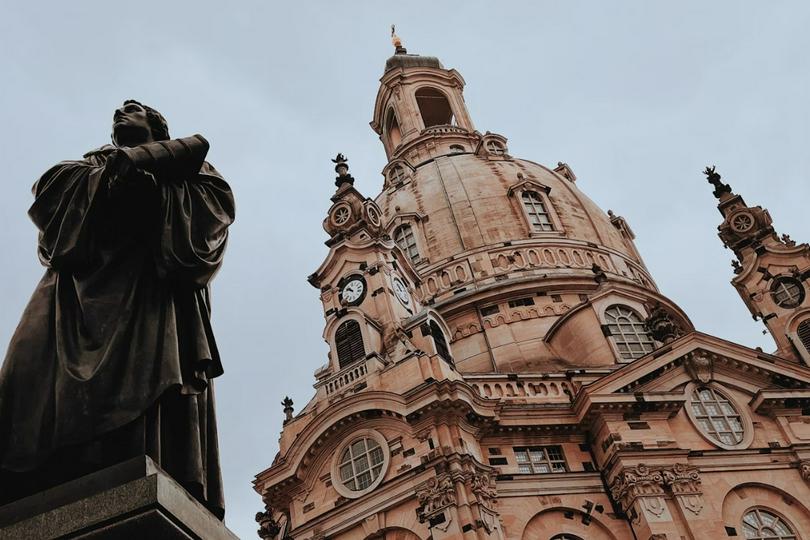 A statue of Martin Luther stands in front of a church building.