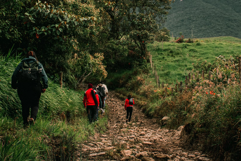 A group of people walked down a rocky road in the mountains on an unknown day.