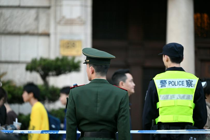 A Chinese policeman and a soldier stood in front of a building on an unknown day.