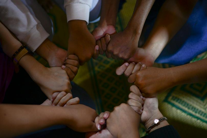 Different people’s clenched hands come together to form a circle.