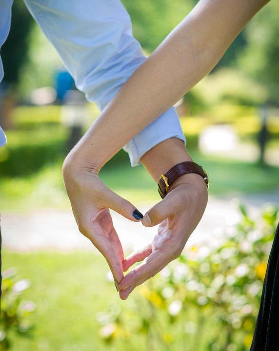A couple makes a sign of a "love" heart.
