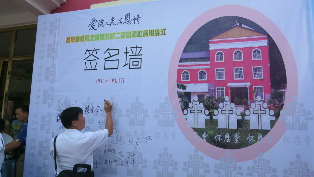 A man signs his name on the signature wall that introduces the dedication of the new church and opening of a service