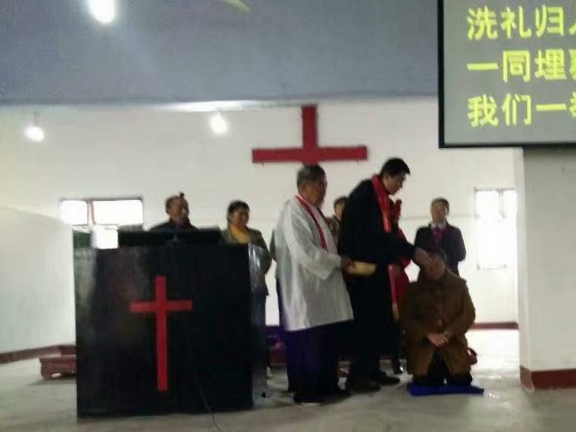 A pastor baptizes a man in Shen'en Church