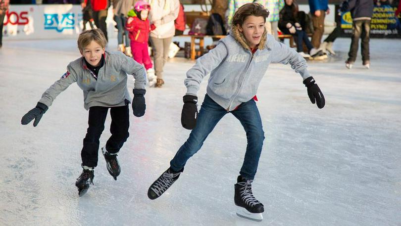 Two children skate on the ice.