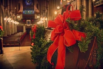 Ribbons and evergreen conifer are used to decorate church pews to celebrate Christmas.