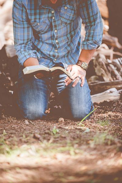 A man reads the Bible on his knees.