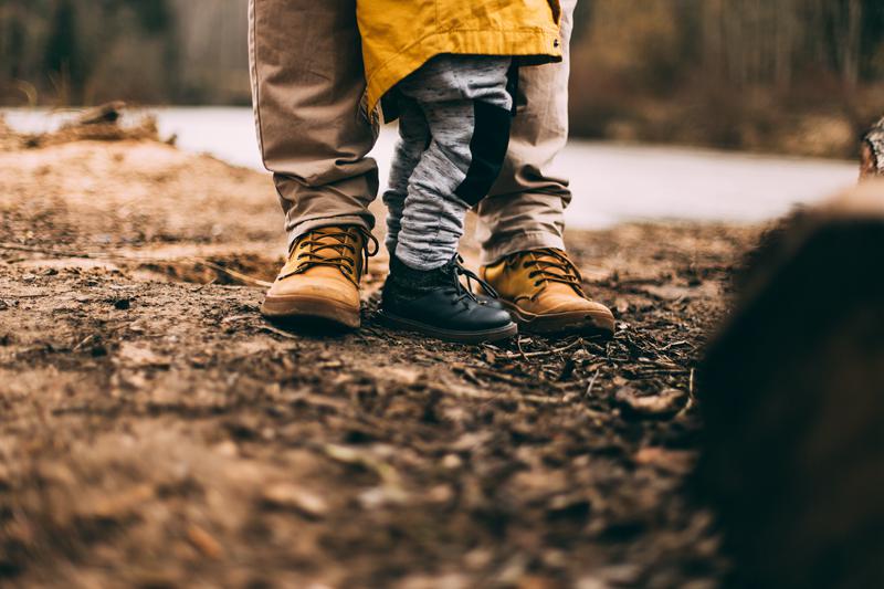 A boy stands with his father. 