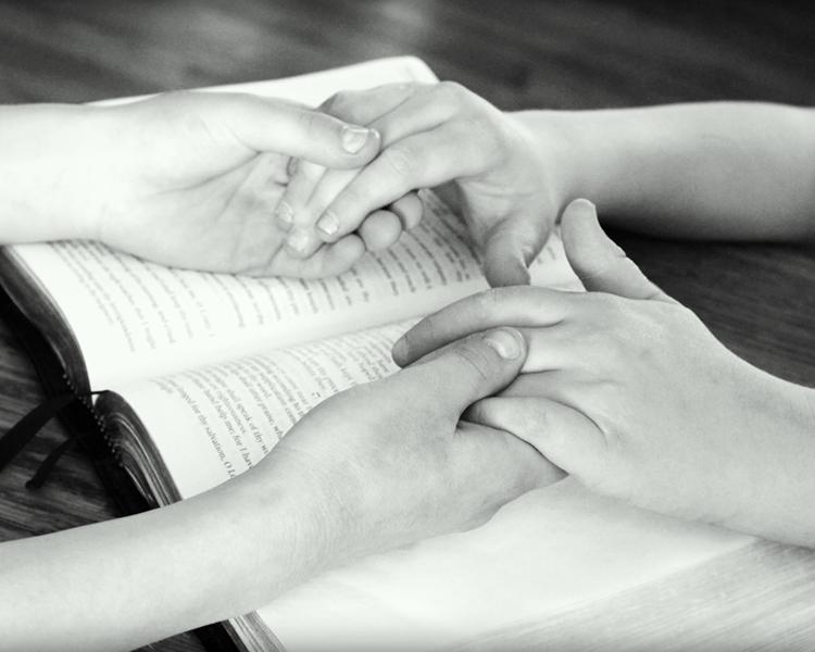Two persons pray with each other. 