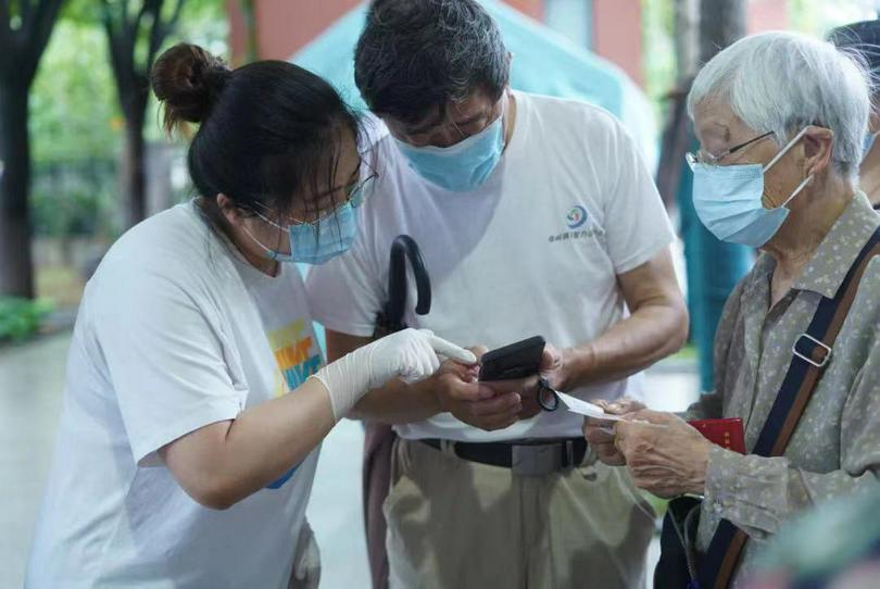 A worker of Nanjing YMCA-YWCA checked a man's health code in Zhiyuan Foreign Language Primary School Testing Point in Jianye District, Nanjing, Jiangsu Province, in late July 2021.