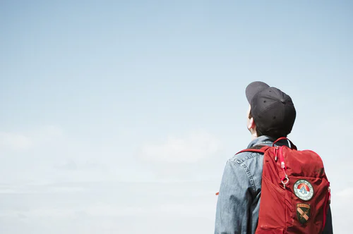 A man with a bag on his back looks at the sky.