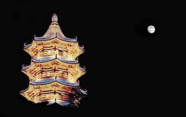 A tower decorated with lights under a full moon at night