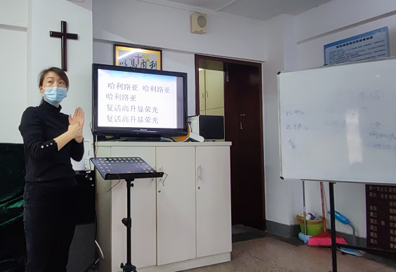 A female believer, surnamed Zhang with normal hearing, in sign language interpreted a Sunday service of Mochou Road Church in Nanjing, Jiangsu, for deaf Christians on January 9, 2022.