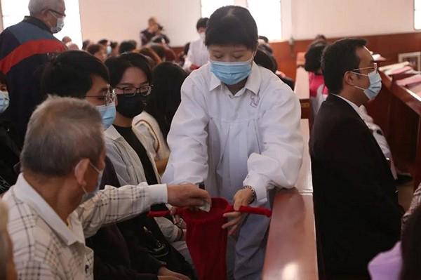 The picture show an aged believer putting some money into an offering box at an unknow date.