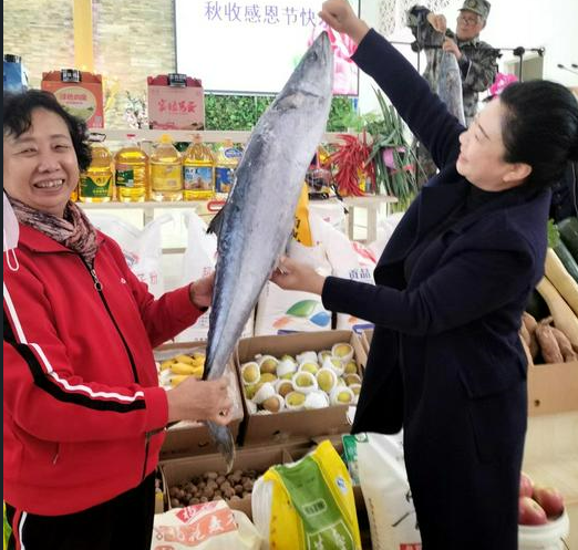 Two believers held big fish with food around after a Sunday service to celebrate the Autumn Harvest Festival in Shuishiying Church, Dalian, Liaoning, on October 16, 2022.