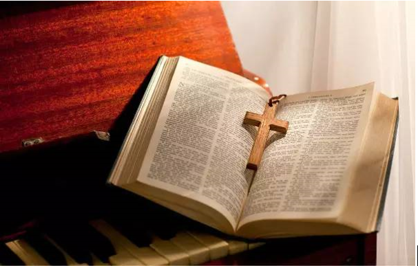 A Bible with a cross on a piano